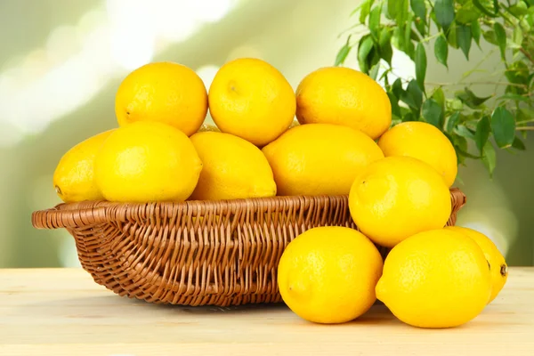 Limones maduros en canasta de mimbre sobre mesa sobre fondo brillante —  Fotos de Stock