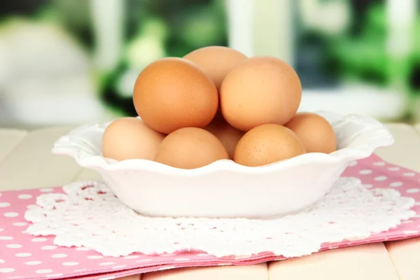 Eggs in plate on wooden table on window background — Stock Photo, Image
