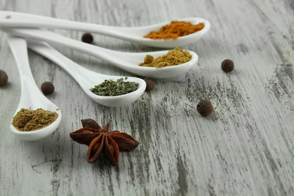 Surtido de especias en cucharas blancas, sobre fondo de madera —  Fotos de Stock