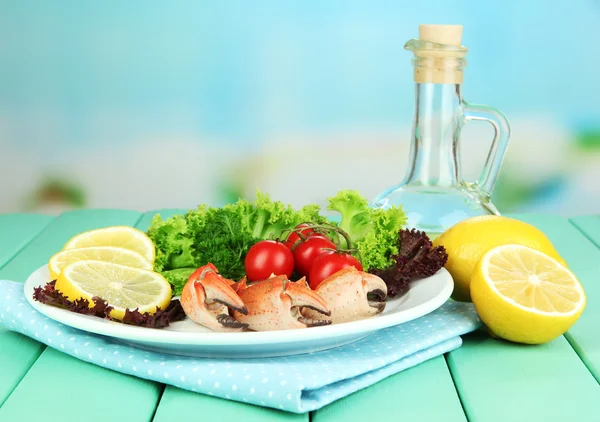 Garras de caranguejo cozidas na placa branca com folhas de salada e tomates, na mesa de madeira, no fundo brilhante — Fotografia de Stock