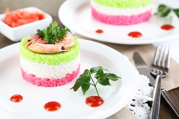 Colored rice on plates on napkins on wooden table — Stock Photo, Image