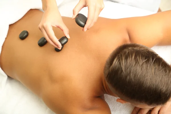 Young man having stone massage in spa salon — Stock Photo, Image