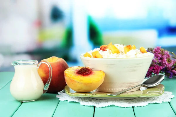 Sour cheese and pieces of fresh peach,on wooden table, on bright background — Stock Photo, Image