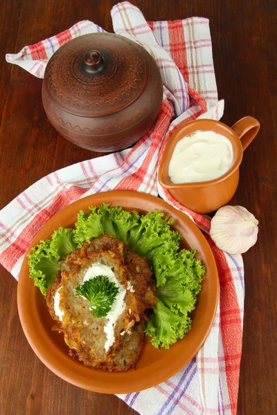 Potato pancakes in pot, on wooden background — Stock Photo, Image