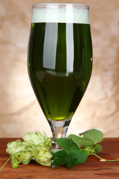 Glas mit grünem Bier und Hopfen, auf Holztisch — Stockfoto