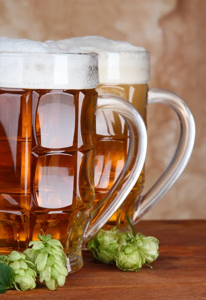 Glasses of beer and hops, on wooden table — Stock Photo, Image