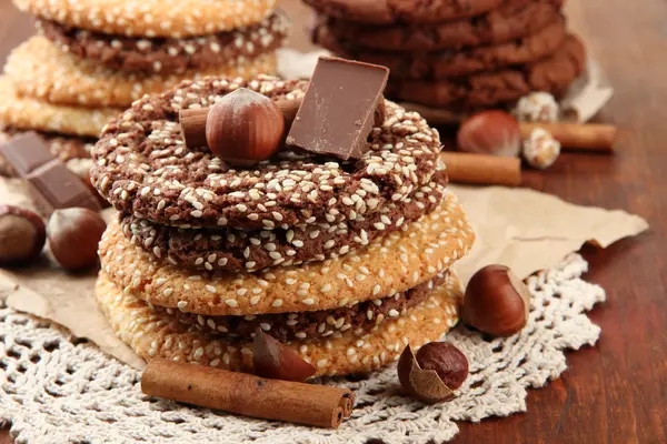 Homemade cookies with sesame seeds, chocolate, on napkin, on wooden background — Stock Photo, Image