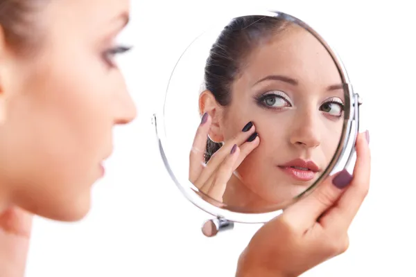 Beautiful girl preens before small mirror isolated on white — Stock Photo, Image