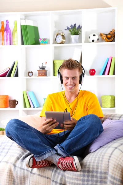 Genç adam tablet ile kanepede rahatlatıcı — Stok fotoğraf