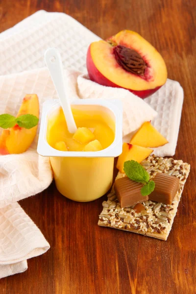 Yogurt saporito con pezzi di frutta fresca, biscotti e fiocchi, su sfondo di legno — Foto Stock