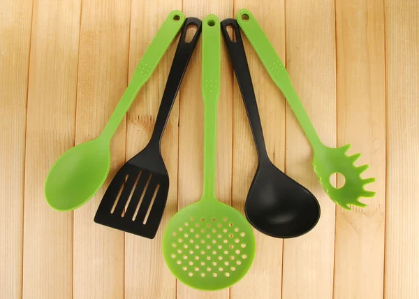 Plastic kitchen utensils on wooden background — Stock Photo, Image