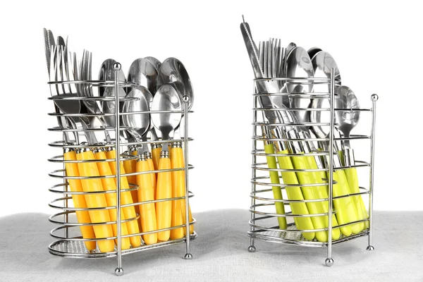 Cuchillos, tenedores y cucharas en soporte de metal sobre mantel sobre fondo blanco —  Fotos de Stock