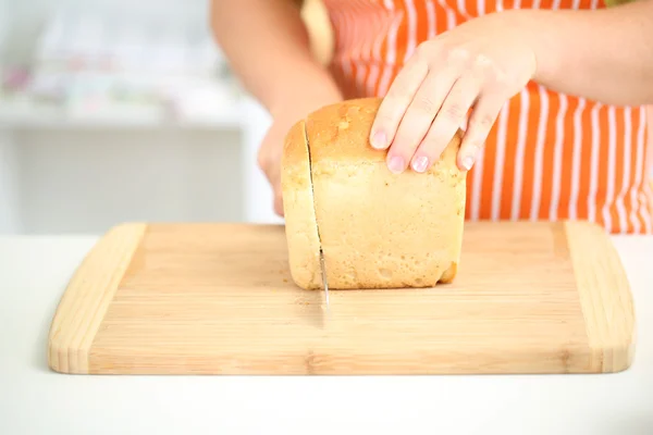 Femme tranchant du pain sur une planche à découper, gros plan — Photo