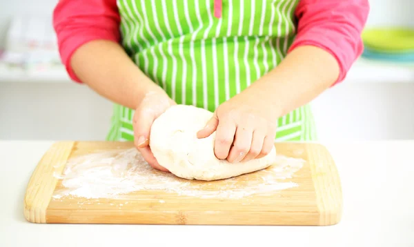 Руки женщины в муке крупным планом смешивают тесто на столе — стоковое фото