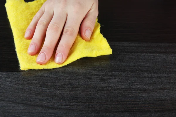 Hand wiping wooden surface with yellow rag — Stock Photo, Image