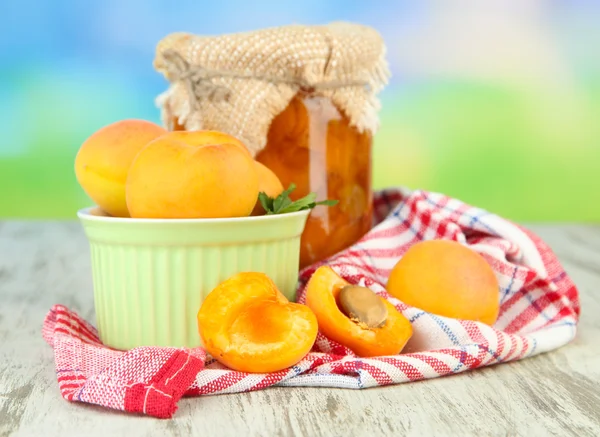 Aprikos sylt i glasburk och färska aprikoser, på träbord, på ljus bakgrund — Stockfoto