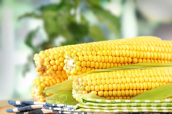 Rå majs på serviet på træbord på vinduesbaggrund - Stock-foto