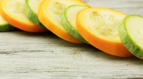 In Scheiben geschnittene gelbe und grüne rohe Zucchini auf Holztisch — Stockfoto