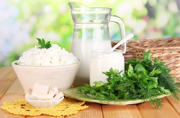 Свіжі молочні продукти з зеленню на дерев'яному столі на природному фоні — стокове фото