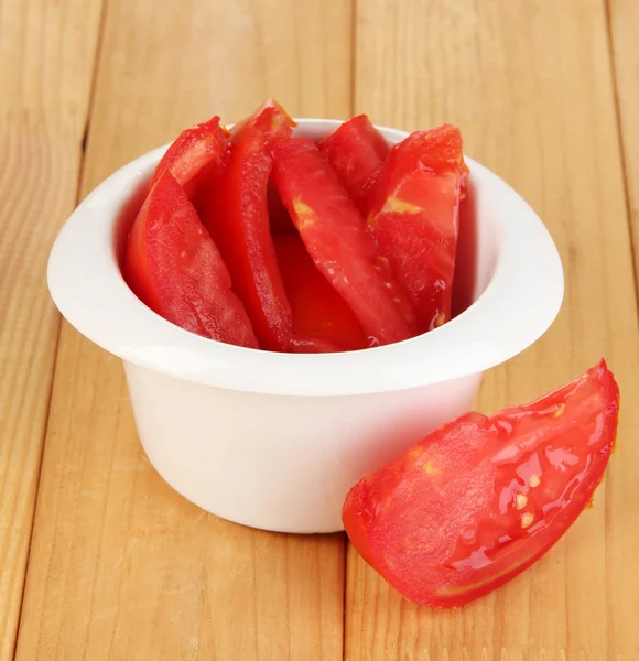 Bright fresh tomato cut up slices in bowl on wooden table close-up — Stock Photo, Image