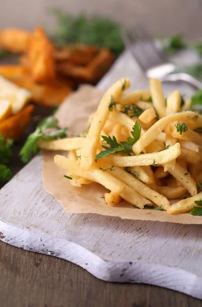 Pommes frites på ritpapper ombord på träbord — Stockfoto