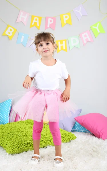 Niña bailando en la cama en la habitación sobre fondo gris de la pared — Foto de Stock