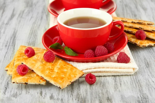 Cups of tea with cookies and raspberries on table close-up