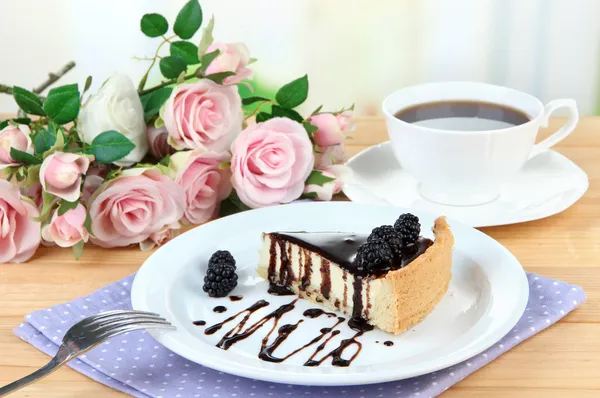 Plak van kaastaart met chocolade saus en blackberry op plaat, op houten tafel, op lichte achtergrond — Stockfoto