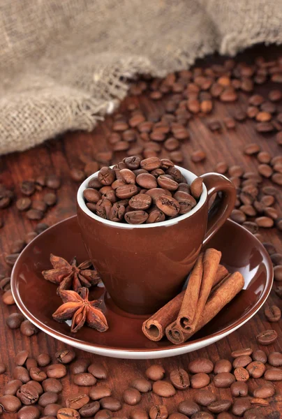 Grãos de café em xícara no fundo de madeira — Fotografia de Stock