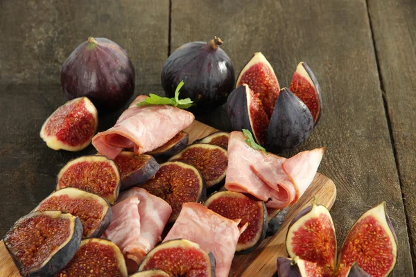 Figues savoureuses avec jambon sur table en bois gris — Photo