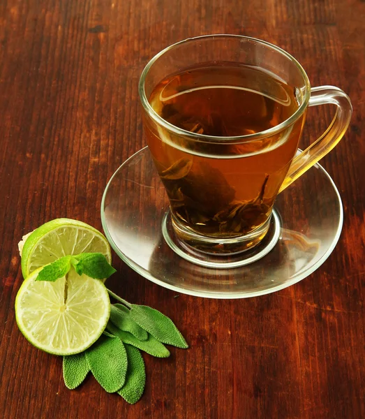 Taza transparente de té verde con lima sobre fondo de madera — Foto de Stock