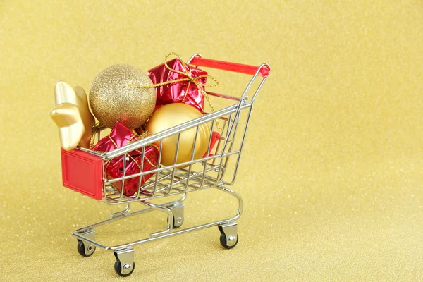 Regalos de Navidad en el carrito de la compra, sobre fondo dorado brillante — Foto de Stock