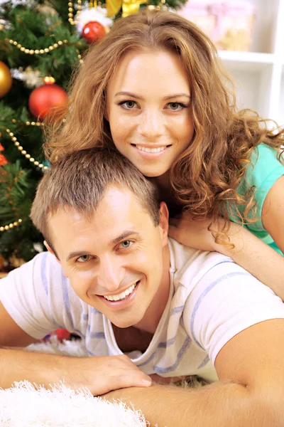 Happy young couple near Christmas tree at home — Stock Photo, Image