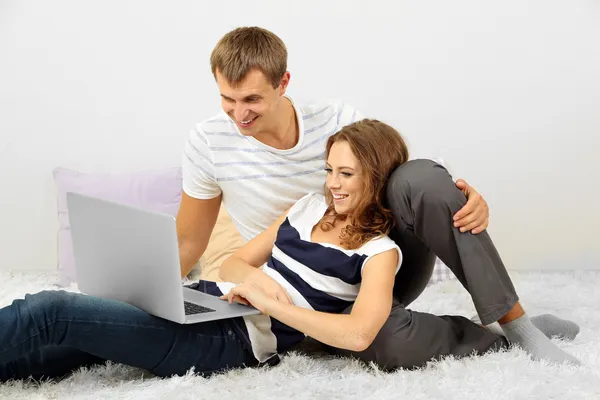 Happy young couple with laptop at home — Stock Photo, Image