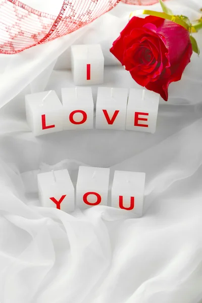 Candles with printed sign I LOVE YOU, on white fabric background — стоковое фото