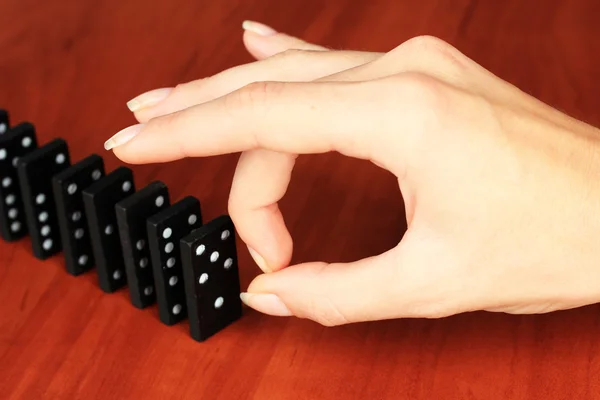 Mão empurrando dominós no fundo de madeira — Fotografia de Stock