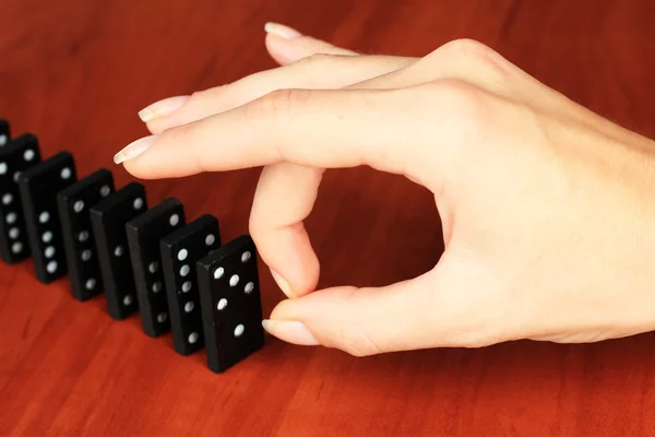 Hand pushing dominoes on wooden background — Stock Photo, Image