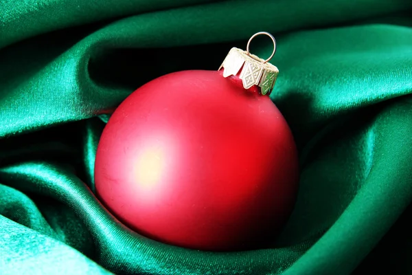 Beautiful Christmas ball on green satin cloth — Stock Photo, Image