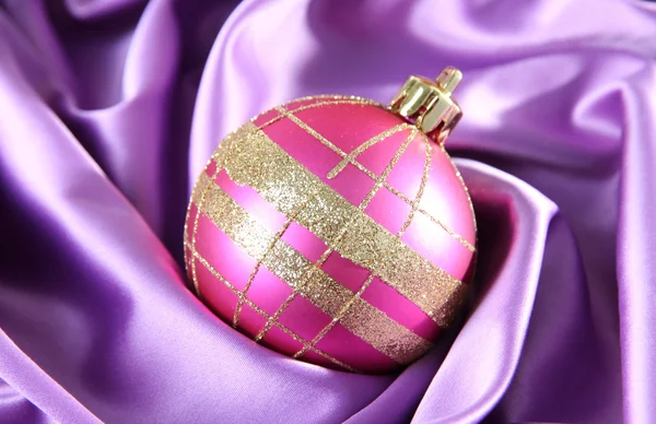 Schöne Weihnachtskugel auf lila Satintuch — Stockfoto