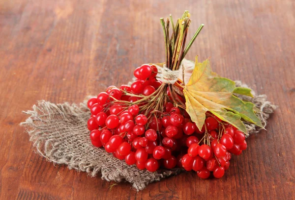 Bayas rojas de viburnum en servilleta de tela de saco, sobre fondo de madera —  Fotos de Stock