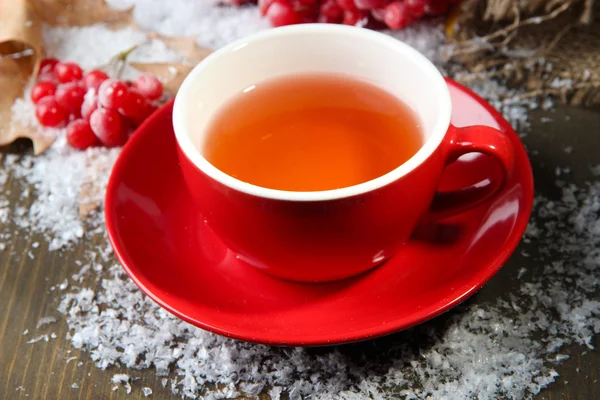 Stilleven met planten van viburnum thee in cup, bessen en sneeuw, op houten achtergrond — Stockfoto