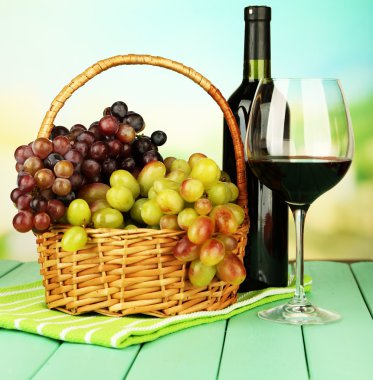 hasır sepet, şişe ve kadeh şarap, parlak zemin üzerinde olgunlaşmış üzümler