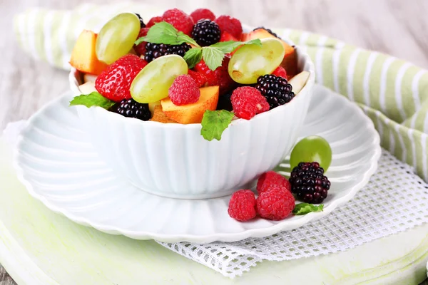 Insalata di frutta in ciotola, su fondo di legno — Foto Stock