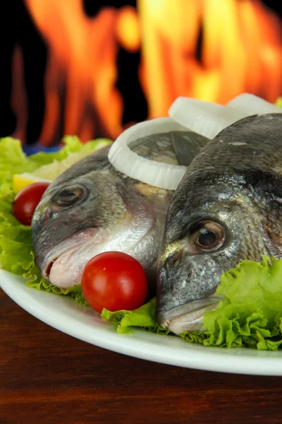 Dorado pescado en la mesa en el fondo de fuego — Foto de Stock