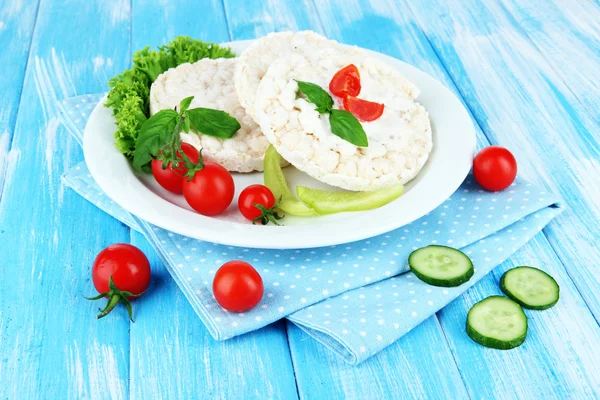 Tasty crispbreads with vegetables on blue wooden background — Stock Photo, Image