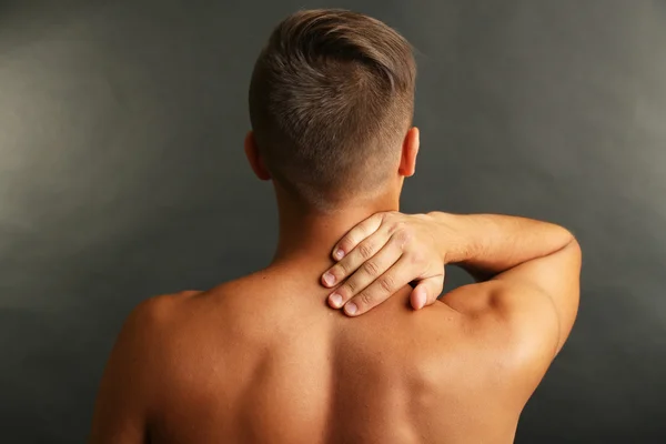 Young man with neck pain on grey background — Stock Photo, Image