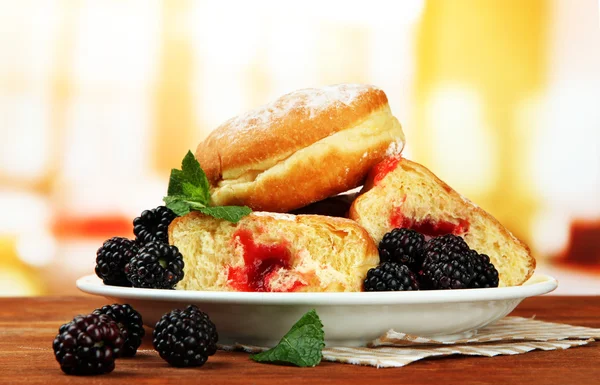 Tasty donuts with berries on wooden table — Stock Photo, Image