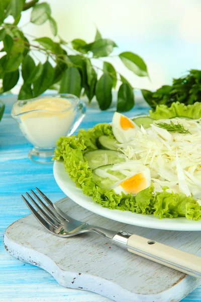 Deliziosa insalata con uova, cavolo e cetrioli sul tavolo di legno blu — Foto Stock