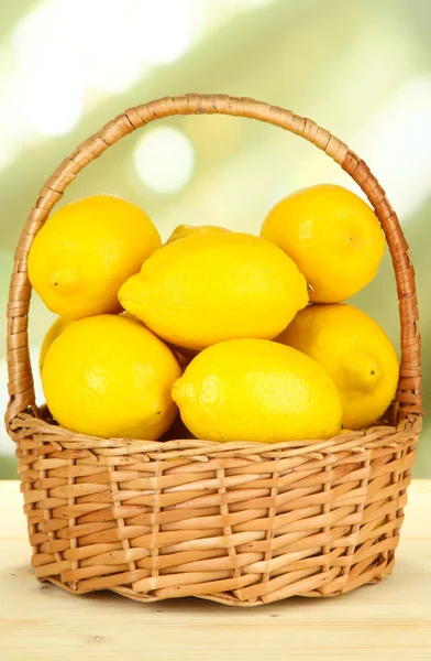 Ripe lemons in wicker basket on table on bright background — Stock Photo, Image