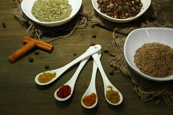 Assortment of spices in white spoons and bowls, on wooden background — Stock Photo, Image